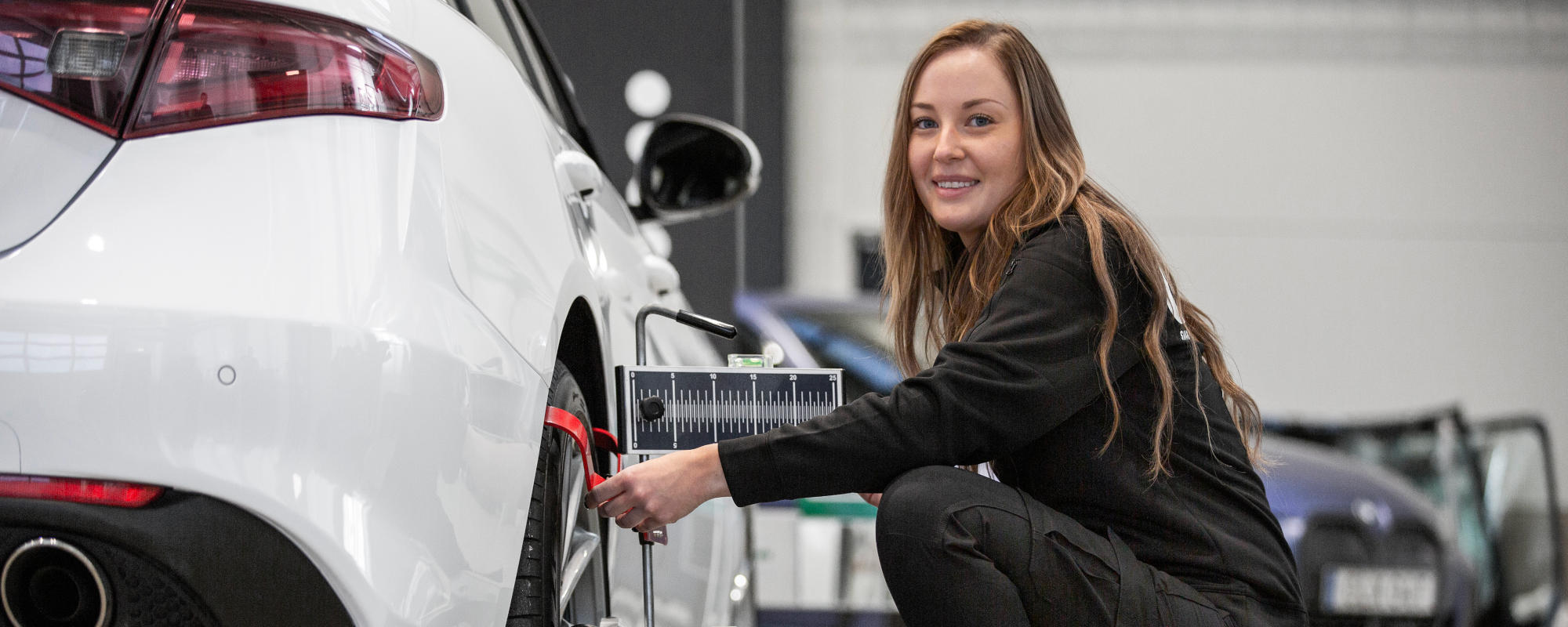 Ryds anställd kvinna använder verktyg på däck för att kalibrera en bil
